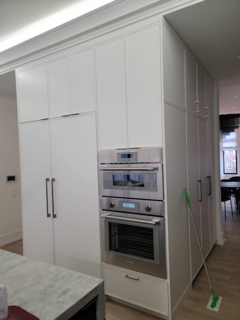 Floor-to-ceiling custom kitchen appliance wall with integrated ovens by T.H. Cabinets