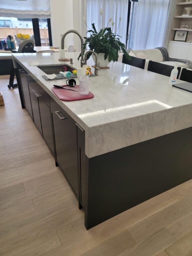 Custom kitchen with dark island cabinetry and stone countertop by T.H. Cabinets
