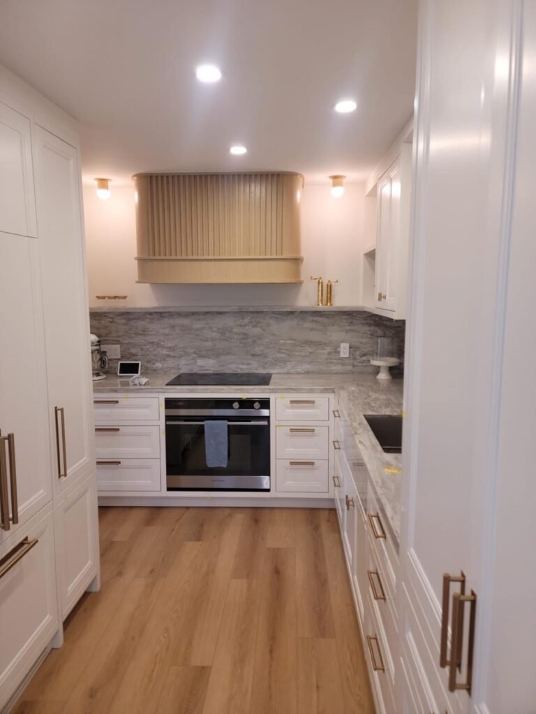 White shaker kitchen with fluted wood custom range hood by T.H. Cabinets