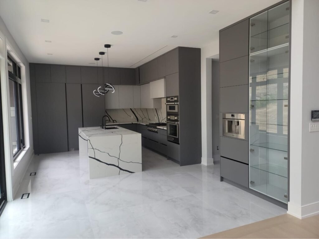 Full-height grey kitchen cabinets with integrated glass display tower by T.H. Cabinets