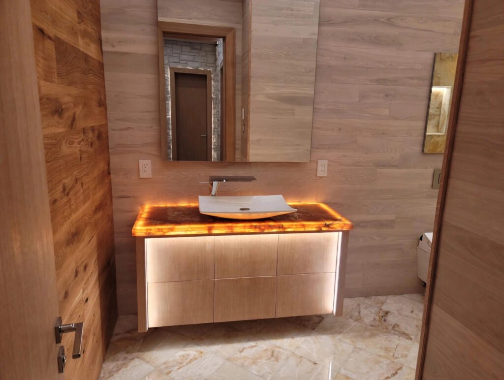 Powder room vanity with backlit onyx countertop and custom cabinetry by T.H. Cabinets