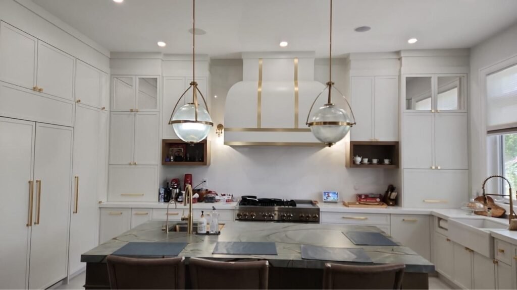 White custom kitchen cabinets with brass-accented range hood by T.H. Cabinets
