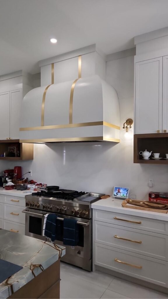 Custom kitchen cabinets in Barrie — white bespoke kitchen with brass range hood by T.H. Cabinets