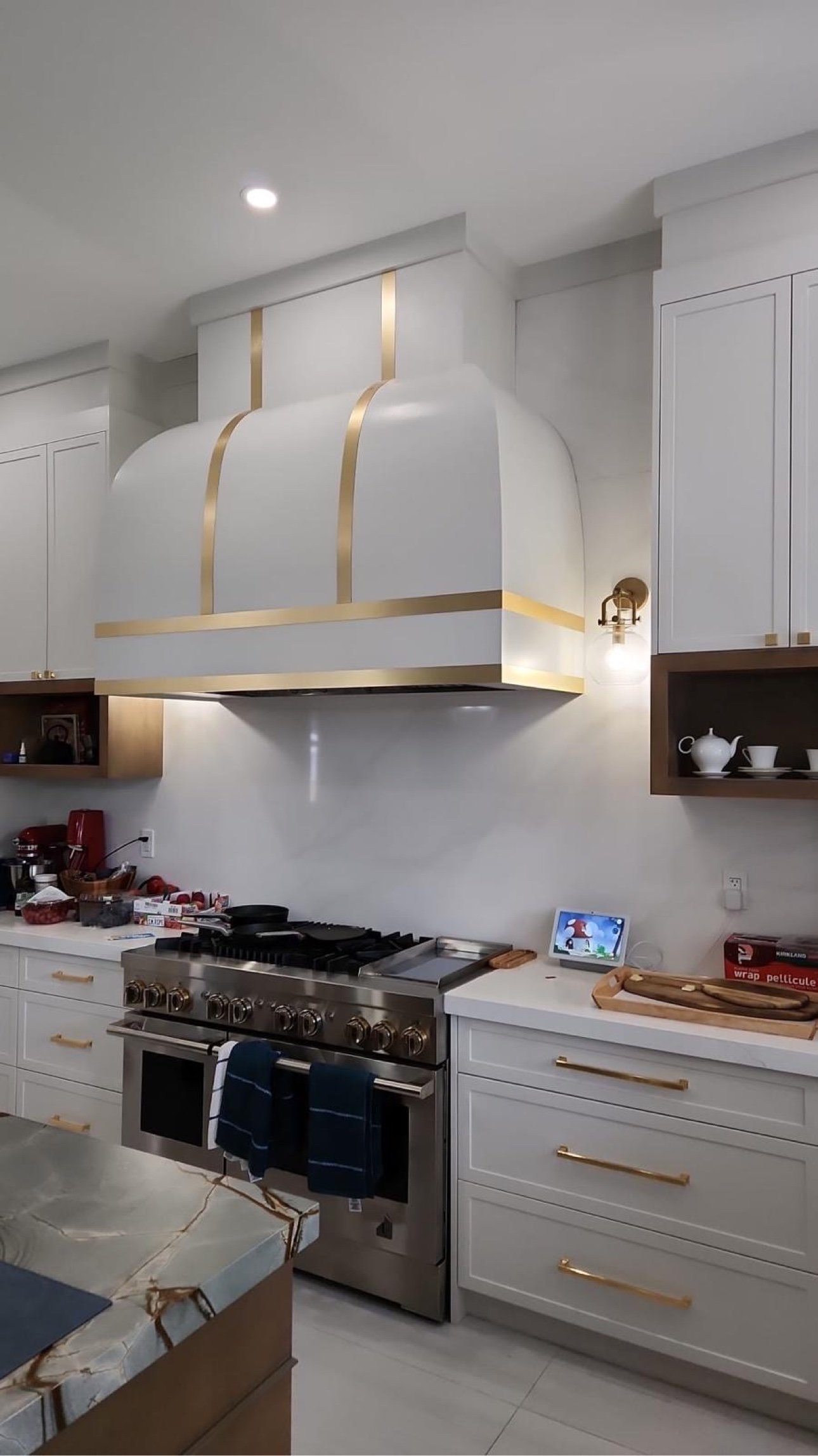 Custom kitchen cabinets in Barrie — white bespoke kitchen with brass range hood by T.H. Cabinets