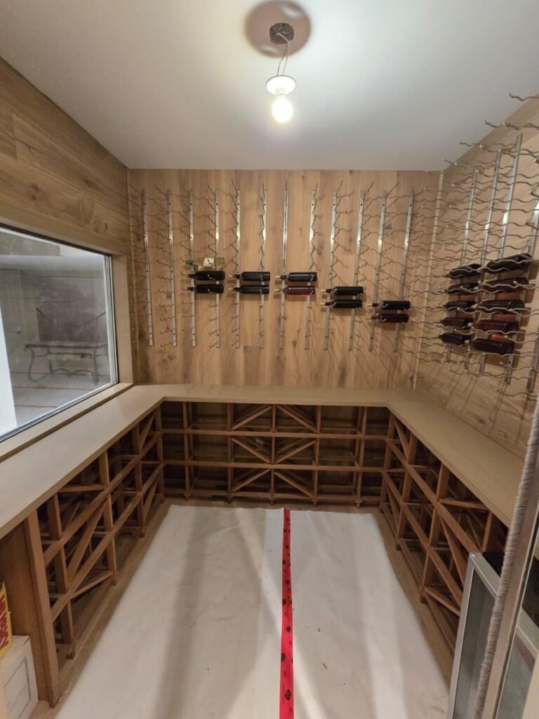 Wine cellar interior with oak paneling and metal bottle racks by T.H. Cabinets